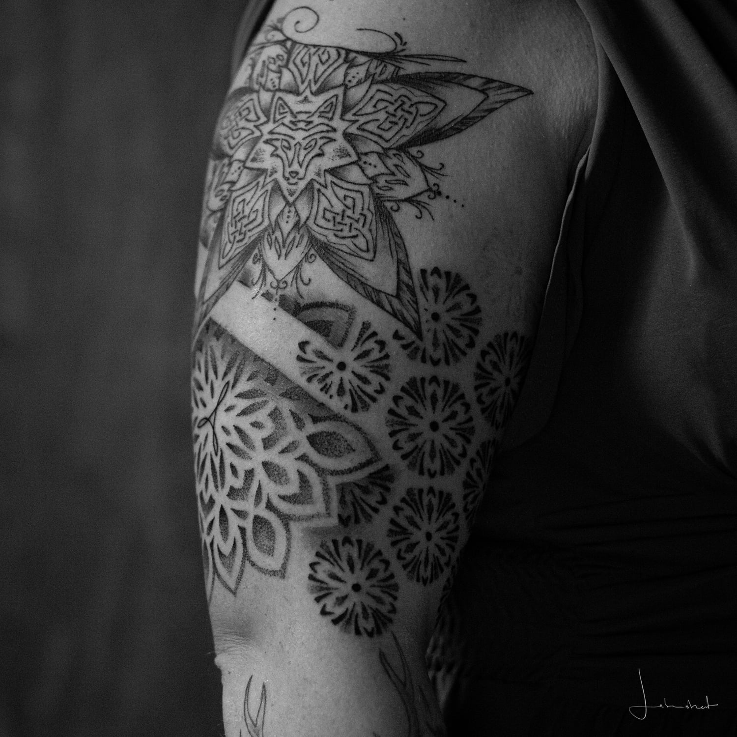 Tattoo eines Mandalas und Mustern auf dem Oberarm